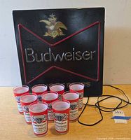 Budweiser wall sign with nine glasses and power cord visible