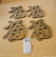 Four brass trivets shaped as Chinese character Fu displayed on tabletop