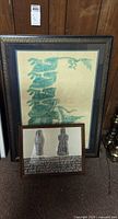 Both framed rubbings standing against wall