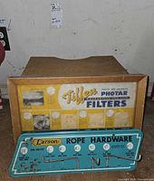 Front view of both items: Tiffen display cabinet and Larson tin sign
