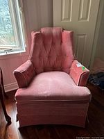 Front view of pink velveteen armchair showing tufted back and padded arms
