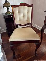 Front view of chair showing wood frame, upholstered seat and tufted back.