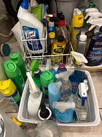 Front view of the cleaning supplies showing spray bottles, trigger spray tops, and plastic containers of various cleaning liquids including Lysol and Windex.