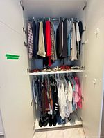 Closet with women's clothing including jackets, tops, blouses hanging on racks, and women's shoes size 37-38 on shelf below.