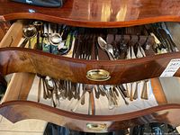 Two wooden drawers filled with assorted cutlery including forks, knives, and spoons with mixed handle materials and sizes.