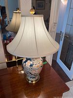 Full view of the enamel floral table lamp with fabric shade on wooden table