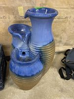 Full view of the ceramic three tier garden fountain showing blue and beige glaze, base texture, and overall shape.