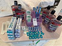 Full overview of the lot showing multiple bottles of Listerine mouthwash, boxes of Sensodyne toothpaste, Oral B toothbrush heads, and GUM soft-picks in a purple container