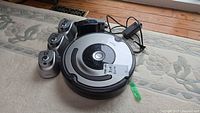 Roomba robotic vacuum cleaner with charging station and three virtual wall units arranged on floor.