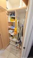 Closet with metal shelving rack, Oreck floor sweeper, Rowenta iron, cleaning supplies, and cloths stacked on shelves.