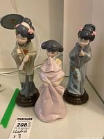 Three figurines group shot on shelf with MaxSold measurement card