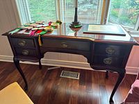 Front view of mahogany-finish writing desk showing five drawers, cabriole legs and scalloped apron