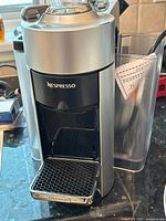 DeLonghi Nespresso EN135S coffee machine, silver and black, with power button visible