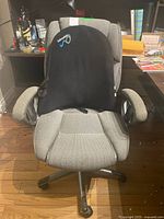 Full front view of gray upholstered office chair with black adjustable back support cushion placed on seat.