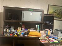 Wide view of dark wooden desk with office supplies and shredder