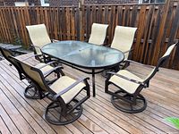 Full view of six chairs and oval glass-top table on wooden deck