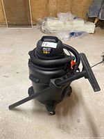 Full view of Shop Vac 3.0 wet/dry vacuum on four casters with hose coiled and floor nozzle attached.
