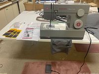 Full view of Singer Heavy Duty sewing machine on table with foot pedal and power cord