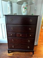 Front elevation of the tallboy dresser with lamps on top, showing all seven drawers and brass ring pulls.