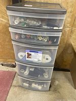 Front view of the plastic storage chest showing contents in drawers such as thread spools and sewing supplies.