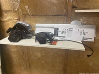 Photo showing Black & Decker jigsaw, mitermate accessory with brackets and screws on a shelf.