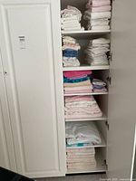 Six-shelf cabinet filled with folded towels in assorted colors and sizes.