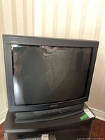 Front view of vintage Sony Trinitron TV, showing curved CRT screen, control buttons, and Sony branding.