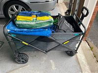 Collapsible wagon loaded with tarps and bags shown from the side
