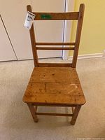 Front view of the wood antique chair showing the plank seat with natural wood finish and two ladder back slats.