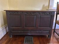 Front view of antique wooden chest showing carved detailing and recessed panels, two bottom drawers missing hardware and unable to open
