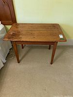 Front view of antique wood table showing the whole piece and condition of the legs and top surface.