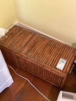 Front and top view of the wooden bamboo style storage box showing its slatted design and one side handle.