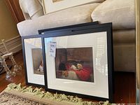 Six framed dog prints with white matting resting against a sofa in black frames.
