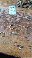 Entire lot laid out on wood surface: filigree earrings, small hoop, two chains including pendant.