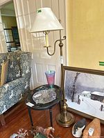 Full view of the floor lamp next to a small round table with glass top and some decorative items.