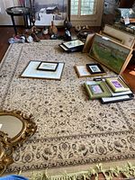 Photo showing the full rug laid out on floor with other art pieces and furniture in background, displaying overall design and fringes.