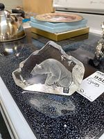 Mats Jonasson glass polar bear figurine on a speckled black surface with neighboring household items in background