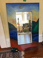 Full view of rectangular mirror with painted landscape wood frame and beveled glass, showing size and details.