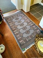 Full view of rectangular rug on hardwood floor showing overall design and fringed edge
