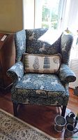 Front view of wingback chair upholstered in patterned fabric with decorative pillow on seat.
