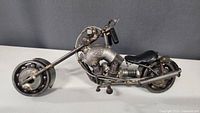 Side view of metal art chopper motorcycle sculpture showing detailed engine and front wheel.