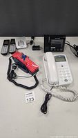Overview of all items including Spider-Man landline phone, white landline phone, two cordless handsets with base, and black alarm clock.