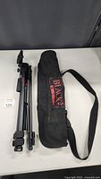 Folded Blacks BX35 camera tripod beside its carrying bag, displayed on table.