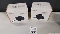 Two boxed Iselector Desktop Chargers on black surface with lot tag.