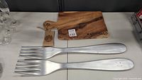 Photo of two extra-large decorative metal wall hanging forks with brushed silver finish placed side by side.