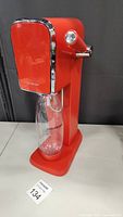 Full view of red SodaStream machine with attached clear bottle showing overall appearance and branding.