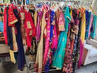 Wide view showing a rack of assorted ladies Indian traditional clothing in multiple colors and styles, hanging on plastic hangers.