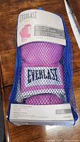 Original packaging of pink Everlast boxing gloves in blue mesh bag with size 12 oz label visible.