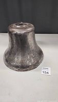 Heavy metal bell standing upright showing full form and texture, measuring approximately 10" high and 12" wide.