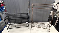 Two metal racks side by side: black metal shoe rack with mesh shelves and bronze finish quilt rack with scroll design.